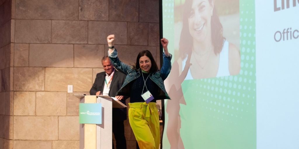 Award winner walking across stage with hands raised in triumph
