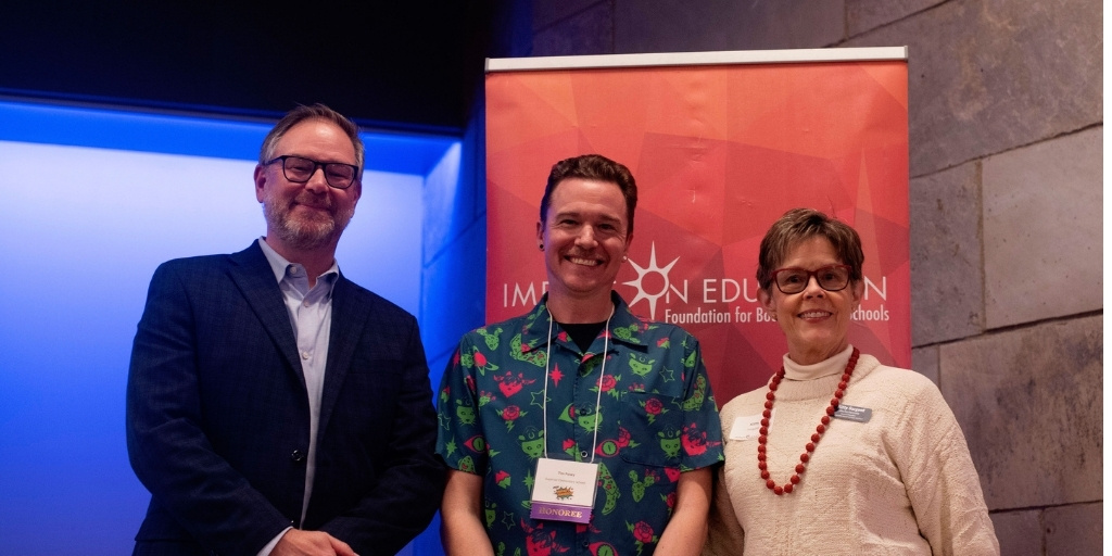 Educator smiling with award and two BVSD leaders on either side