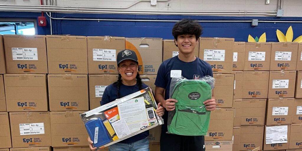 Mother and son volunteer duo holding school supplies