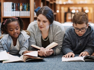 Educator and two students reader on the floor together