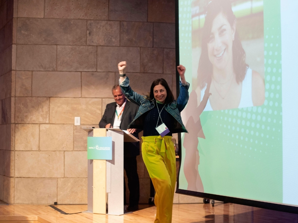 smiling teacher waving arms and walking across stage