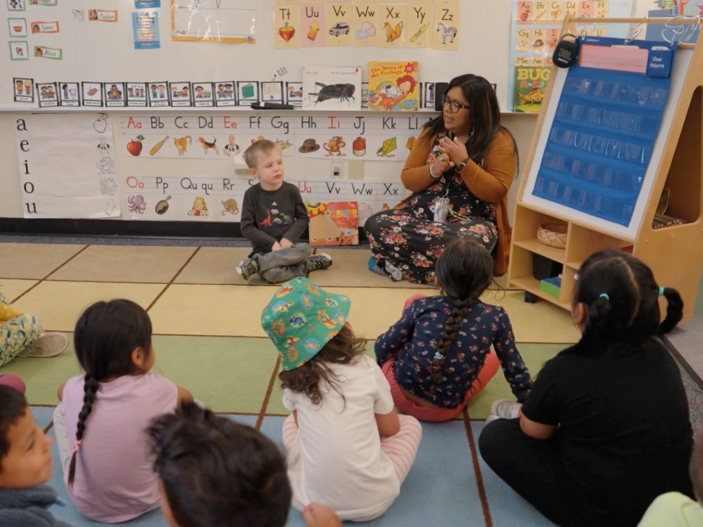 Preschool class sitting on the rug with teacher