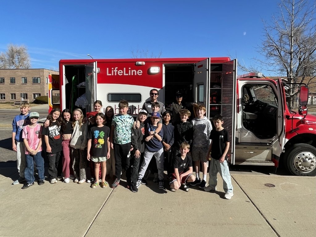 group of students smiling in front of ambulance