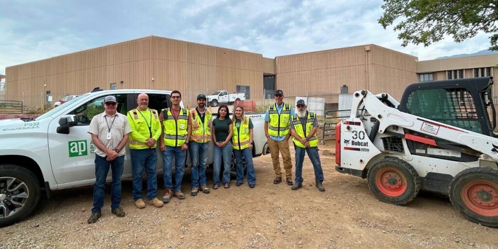 Student and construction crew near equipment in safety vests
