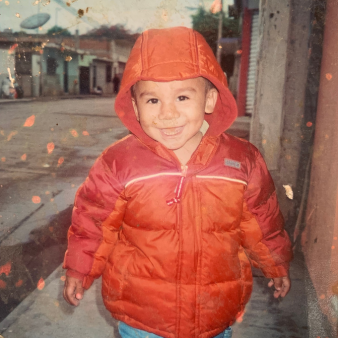 Josue as a child wearing an orange jacket