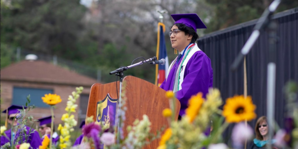 Josue in purple cap and gown delivering the Boulder High School commencement address
